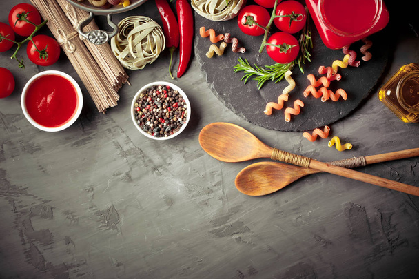 Pasta in a composition with vegetables and kitchen accessories on an old background - Foto, Imagen