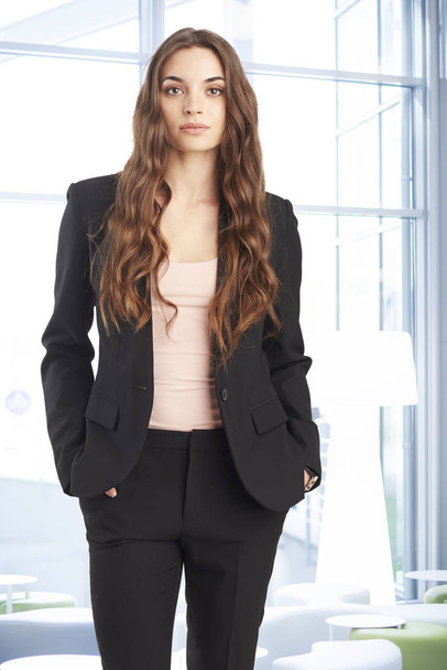 Μια ελκυστική νεαρή βοηθός πωλήσεων επιχειρηματίας που στέκεται στο την αίθουσα πριν από επαγγελματική συνάντηση. - Φωτογραφία, εικόνα