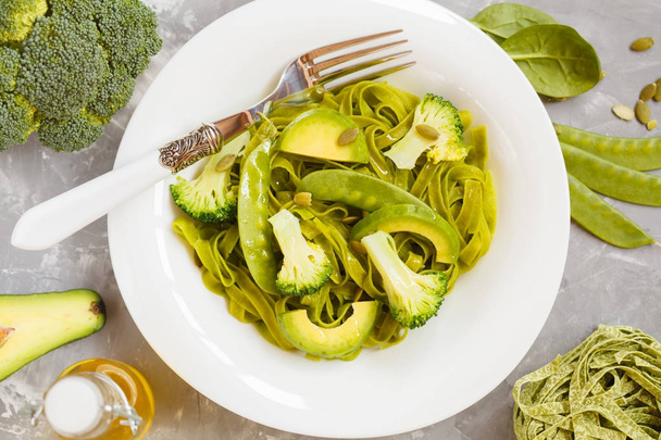 Healthy spinach pasta with broccoli, avocado, pumpkin seeds and  - Фото, изображение