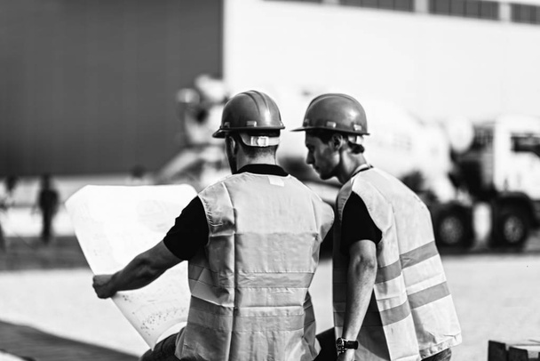 Trabalhadores da construção com planos no canteiro de obras
 - Foto, Imagem