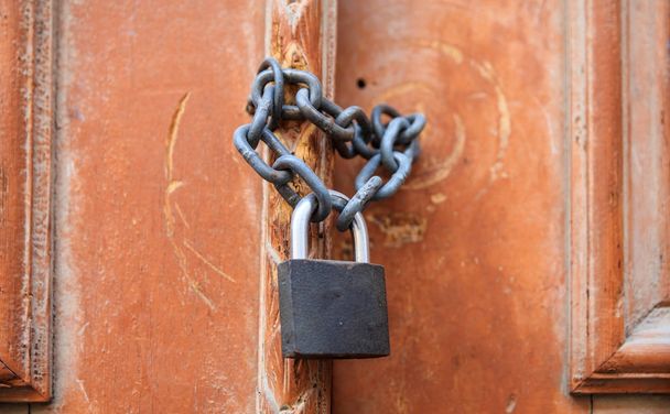 Padlock with chain blocking the entrance. Wooden door, close up view. - Φωτογραφία, εικόνα