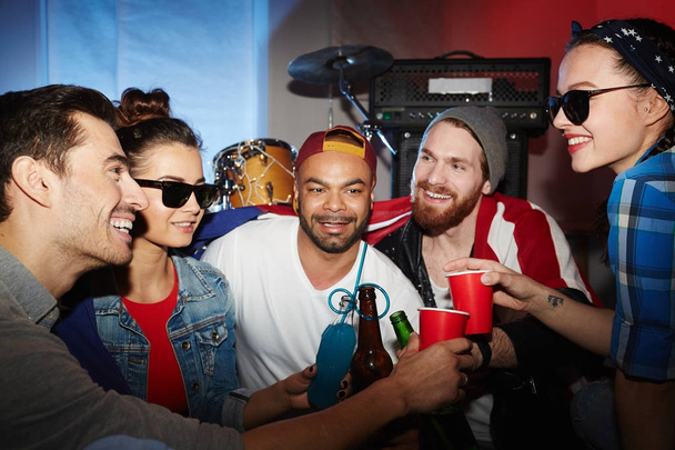 Мульти-етнічна група усміхнених молодих людей висить у нічному клубі на вечірках і тортах з пивом, розважаючись
 - Фото, зображення