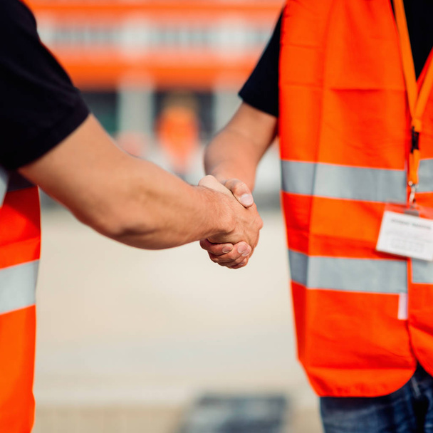 Építőipari munkavállalók kézfogás építkezésen találkozó után - Fotó, kép
