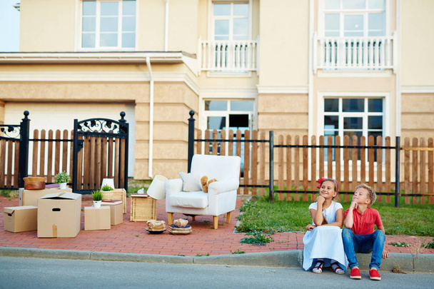 Funny siblings sitting by road and waiting for parents during relocation - Photo, Image