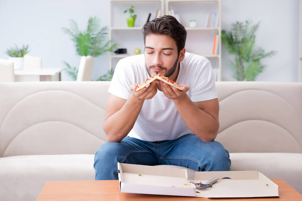 Az ember pizzát eszik, otthon eszik, pihentető pihen. - Fotó, kép