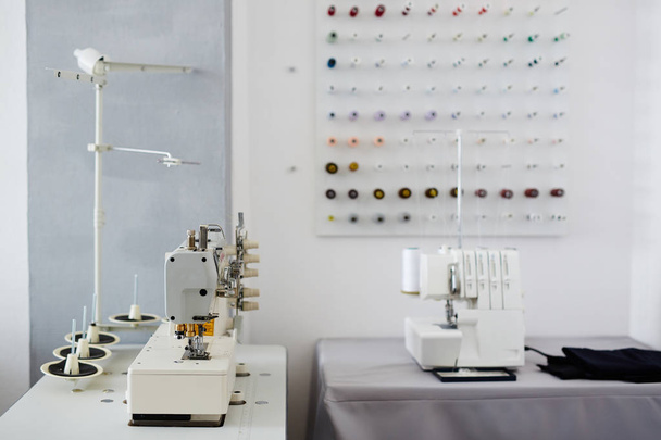 Imagen de fondo de estudio de sastrería vacía y mesas con máquina de coser y serger en ella
 - Foto, Imagen