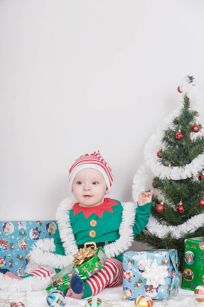 Boy in Christmas Elf costume. A baby near a Christmas tree. - Φωτογραφία, εικόνα