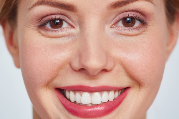 Close-up shot hezká dívka s hnědýma očima a okouzlující úsměv, při pohledu na fotoaparát proti bílým pozadím - Fotografie, Obrázek