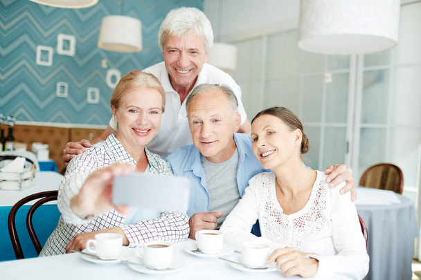 Sorrindo amigos seniores fazendo selfie durante seu encontro no café
 - Foto, Imagem