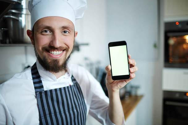 Smiley baker showing smartphone touchscreen - Fotó, kép