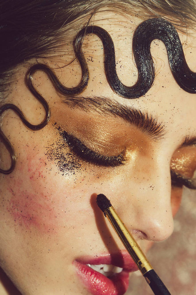 Pretty girl putting holiday glitter eyeshadow makeup - Фото, изображение