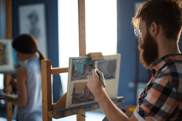Bearded guy painting in studio of art - Fotoğraf, Görsel