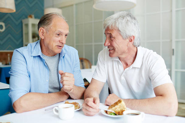 Communication of two friendly senior men by cup of tea and dessert in cafe - Photo, Image