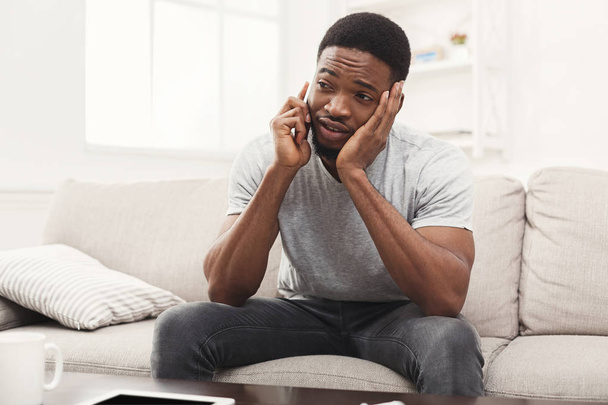 Trauriger junger Mann telefoniert zu Hause mit Handy - Foto, Bild