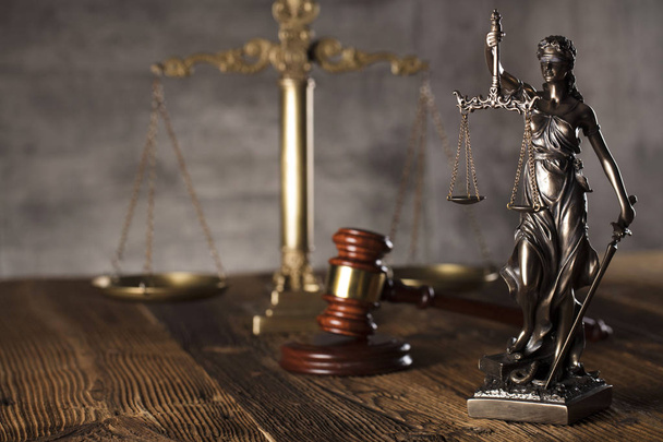 Estatua de justicia y mazo del juez sobre fondo de piedra y mesa rústica de madera
. - Foto, Imagen