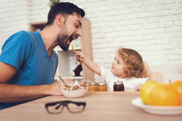 A man spends time with his son. The father of boy is engaged in raising child. Baby is feeding his father. The boy is having breakfast with his father. - Fotoğraf, Görsel