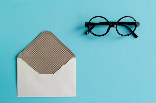 Picture of white envelope and black round glasses over blue back - Foto, Imagem
