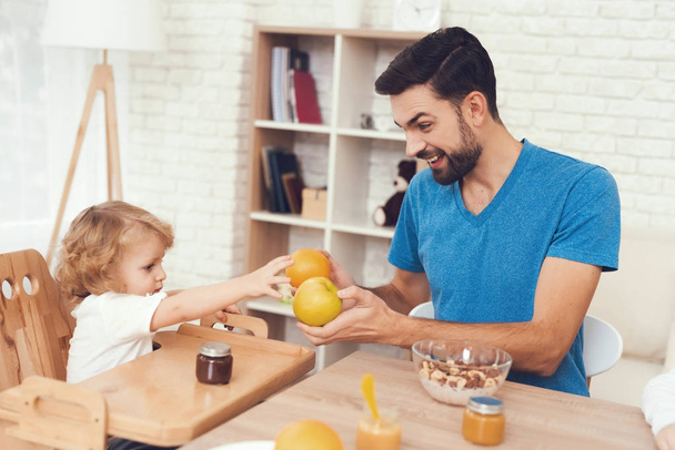A man spends time with his son. The father of boy is engaged in raising child. Father feeds his son. The boy is having breakfast with his father. - Photo, image