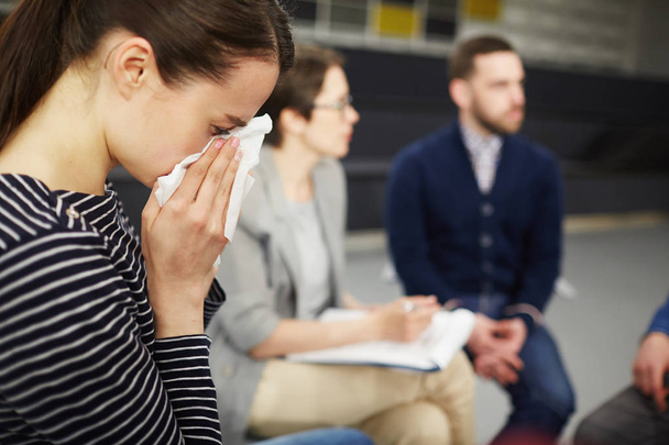 Crying woman wiping her tears with handkerchief with groupmates communicating on background - Photo, Image