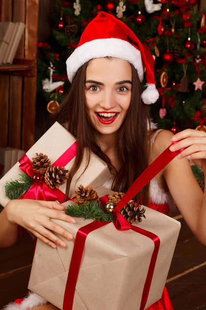 Young happy woman in red santa hat and red dress near new year t - Foto, Imagen