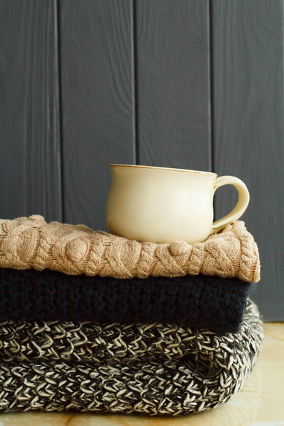 Picture of cozy sweaters and cup of coffee or tea over grey back - Photo, Image