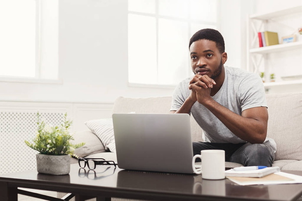 Young thoughtful man at home messaging online on laptop - Photo, Image