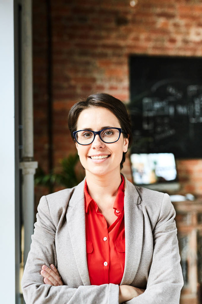 Талия портрет уверенного предпринимателя средних лет, смотрящего в камеру с зубастой улыбкой, стоя у окна современного офиса
 - Фото, изображение