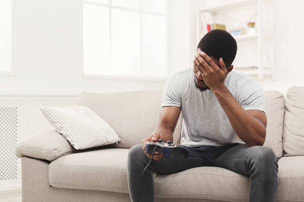 Unhappy young man at home playing video games and loses - Fotó, kép