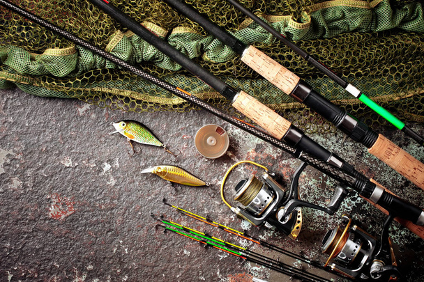 Рыболовные стержни и прядильни в композиции с аксессуарами для рыбалки на старом фоне на столе
 - Фото, изображение