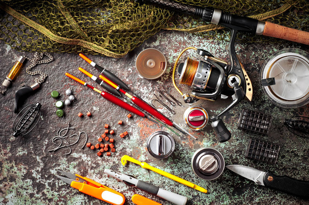 Fishing rods and spinnings in the composition with accessories for fishing on the old background on the table - Foto, imagen