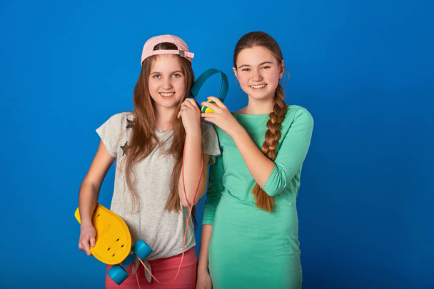 Teen girl loves to listen to the song with headphones.Laughing female friends listen to music. - Zdjęcie, obraz