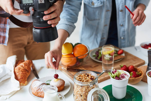 Fotografo che spara cibo sul tavolo mentre il suo assistente lo aiuta
 - Foto, immagini