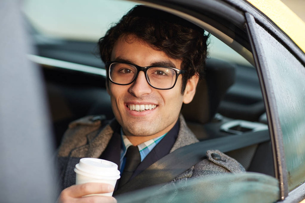 Homem feliz com bebida quente olhando através da janela do táxi
 - Foto, Imagem