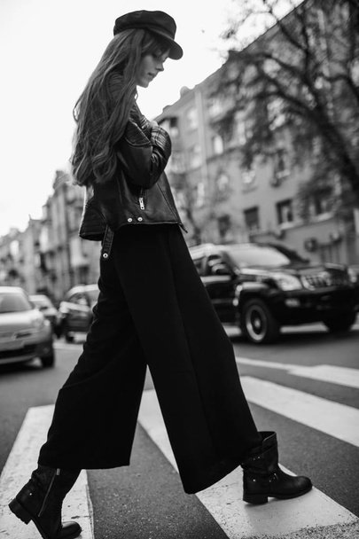 Beautiful girl with sunglasses. A model in a stylish wide-brimmed hat at a pedestrian crossing. Harmoniously similar clothes in gray tones. Street style shooting. Women's fashion. - 写真・画像