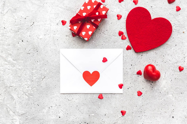 White envelope with hearts and gift box. Flat lay composition - Valokuva, kuva