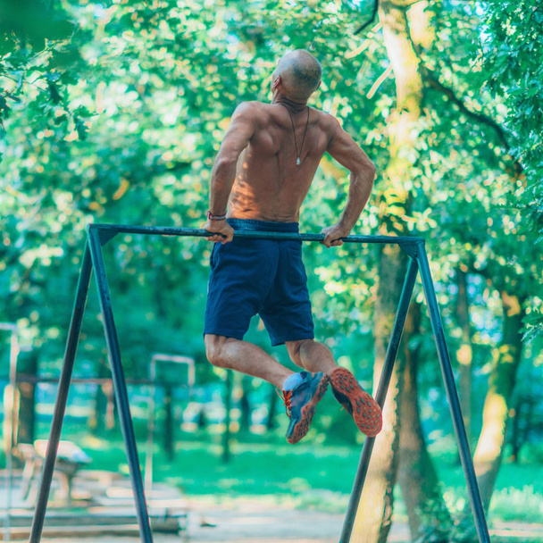 Senior male exercising outdoors in public park - Фото, изображение