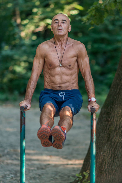 Senior male exercising outdoors in public park - Photo, Image