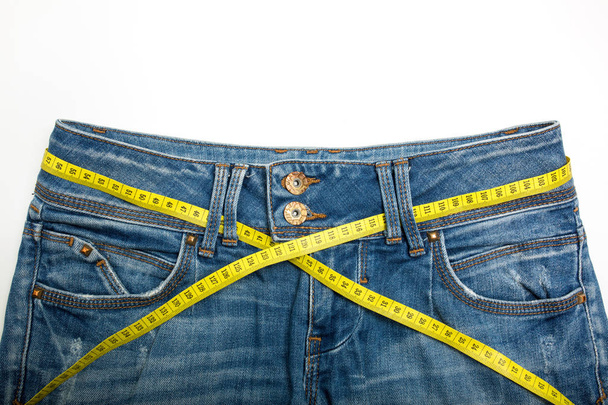Jeans and the measure tape on a white background - Photo, Image