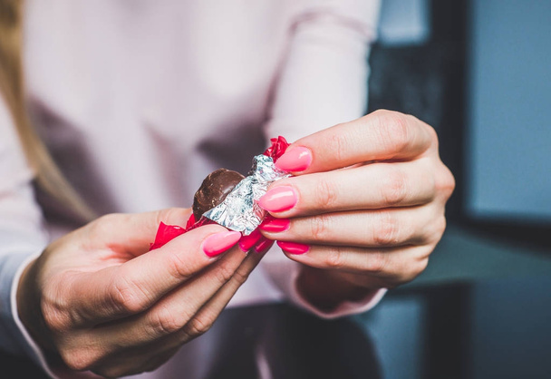 Czekolada w ręce kobiety, otwierając czekoladki. Kobieta trzyma w ręku chocolat, puste, zużyte chocolatier, jedzenie czekolady, Otyłość, Niezdrowe jedzenie, słodkości. - Zdjęcie, obraz