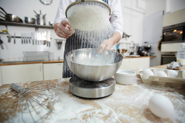 Pastelaria-chef peneirando farinha de trigo para a massa
 - Foto, Imagem