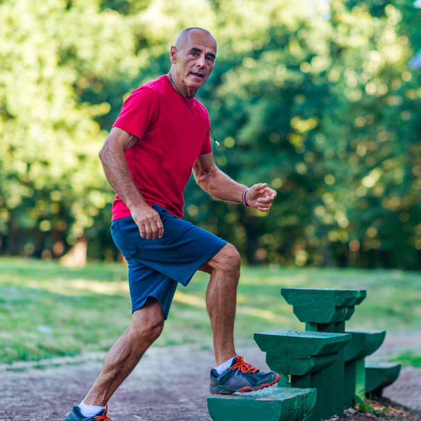 Senior male exercising outdoors in public park - Foto, afbeelding
