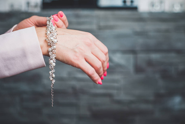 Una mujer lleva un brazalete en la mano. Poniendo en la palma de un dedo, adornos. Diamantes, joyas de plata, objetos de oro, piedras preciosas. La mujer quiere lucir hermosa para la noche, concepto
. - Foto, imagen