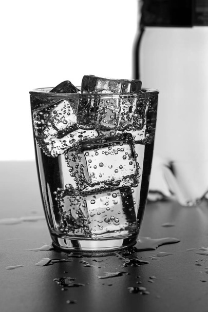 ein Glas Wasser mit Eiswürfeln auf einer nassen Oberfläche - Foto, Bild