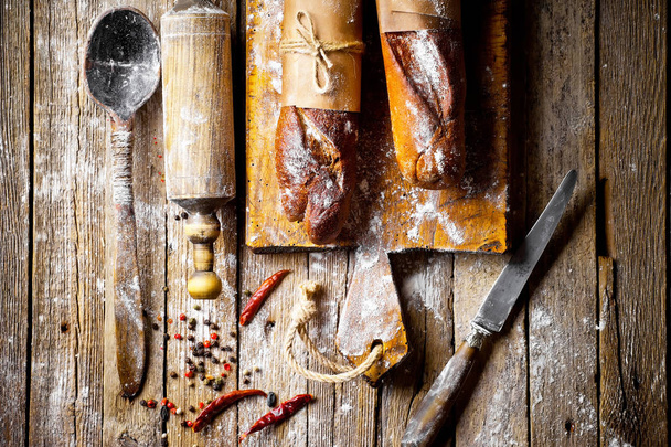 Ψωμί και αρτοσκευάσματα σε μια σύνθεση με αξεσουάρ κουζίνας σε ένα παλιό φόντο - Φωτογραφία, εικόνα
