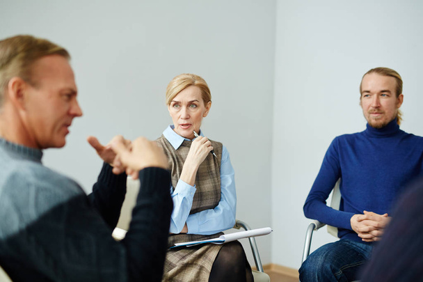 Портрет зрілого професійного психолога, який дає вказівки пацієнтам психічного здоров'я, слухаючи їхні проблеми в групі підтримки
 - Фото, зображення