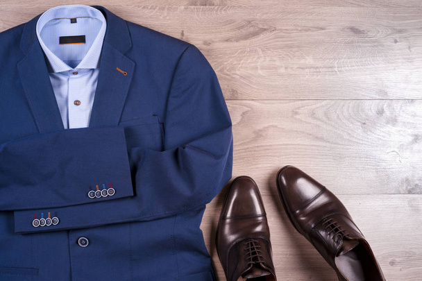 conjunto de roupas masculinas clássicas - terno azul, camisas, sapatos castanhos, cinto e gravata em fundo de madeira. - Foto, Imagem