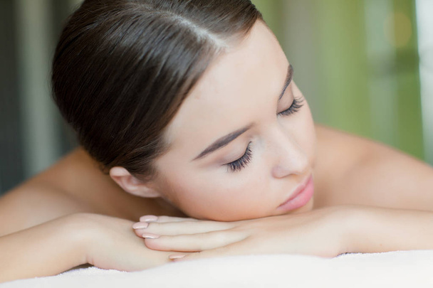 Relaxed girl with closed eyes lying in spa salon before bodycare procedure - Photo, Image