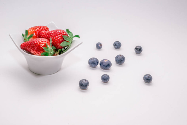 Varias frutas frescas dispuestas en recipientes sobre la mesa. Fresas frescas, naranjas, bayas
. - Foto, Imagen