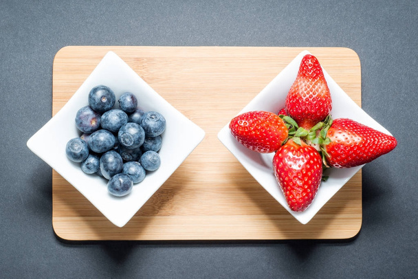Divers fruits frais disposés dans des récipients sur la table. Fraises fraîches, oranges, baies
. - Photo, image
