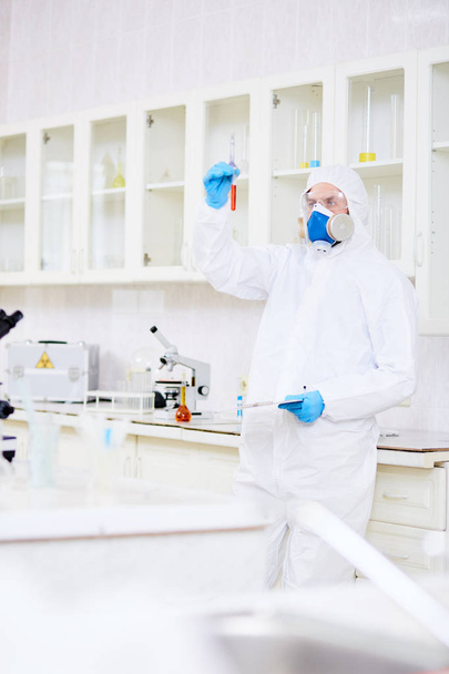 Ученый в защитном покрытии, противогазе, очках и перчатках, работающих с опасными веществами
 - Фото, изображение